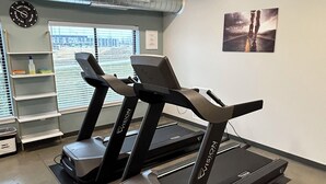 A gym with two treadmills, a clock, and a motivational poster on the wall.