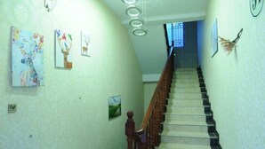 A staircase with a wooden handrail, a light fixture, and wall-mounted artwork. - Rahm Holiday Theme Hotel (Xiaojin)