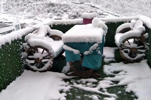 A snow-covered vehicle with a blue tarp and a pink object on top, parked on a snow-covered surface. - Rahm Holiday Theme Hotel (Xiaojin)