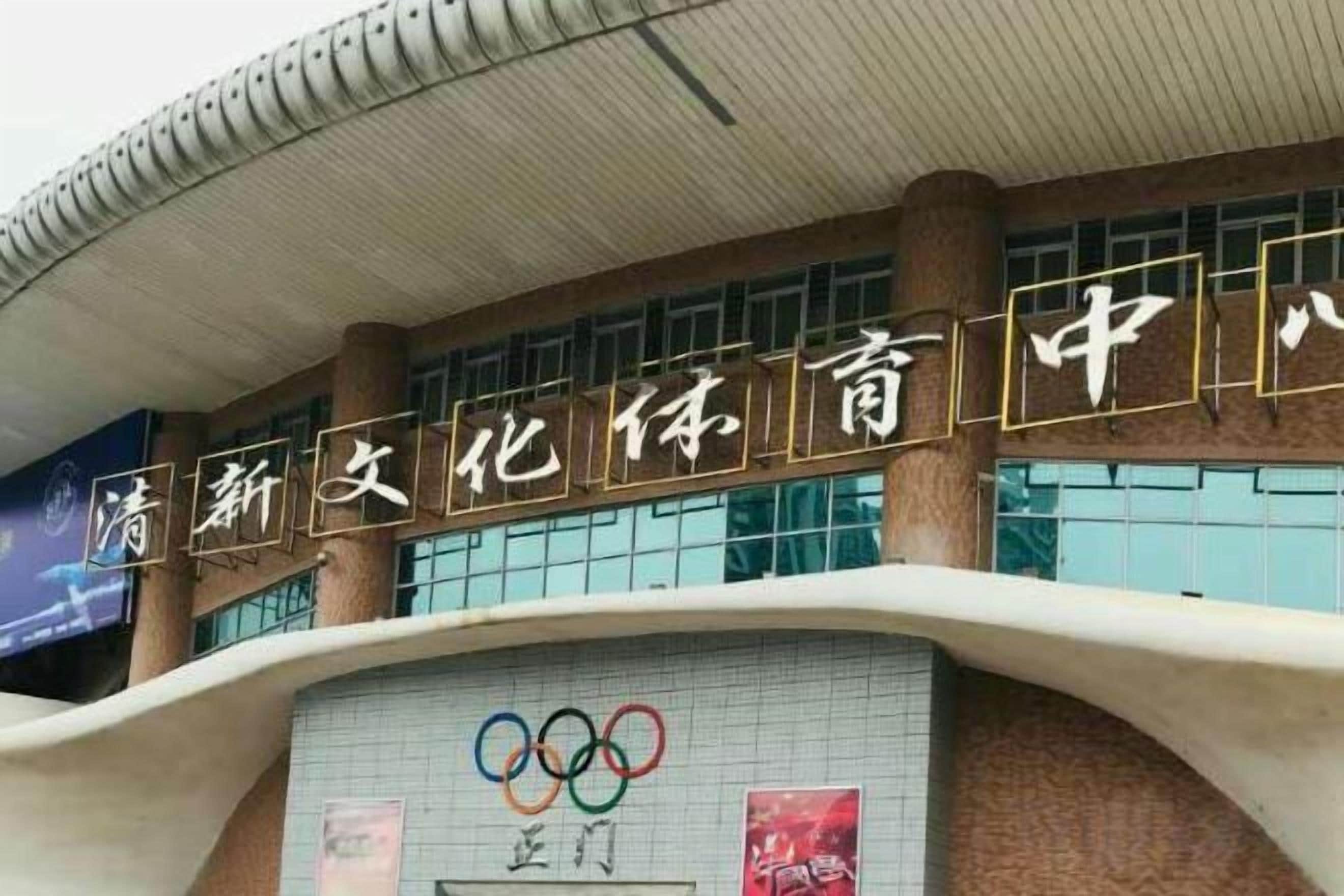 A building with a sign that reads '清新文化体育中心' and the Olympic rings logo.
