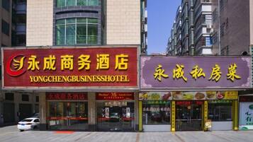 Ein Gebäude mit zwei Schaufenstern, wobei das eine mit 'Yongcheng Business Hotel' und das andere mit 'Yongcheng Private Room' beschriftet ist.