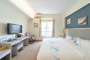 A hotel room with a bed, a desk, a television, a window with curtains, and artwork on the wall.