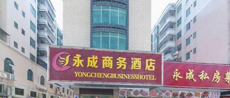 A hotel with a prominent sign, multiple floors, and a parking area in front.