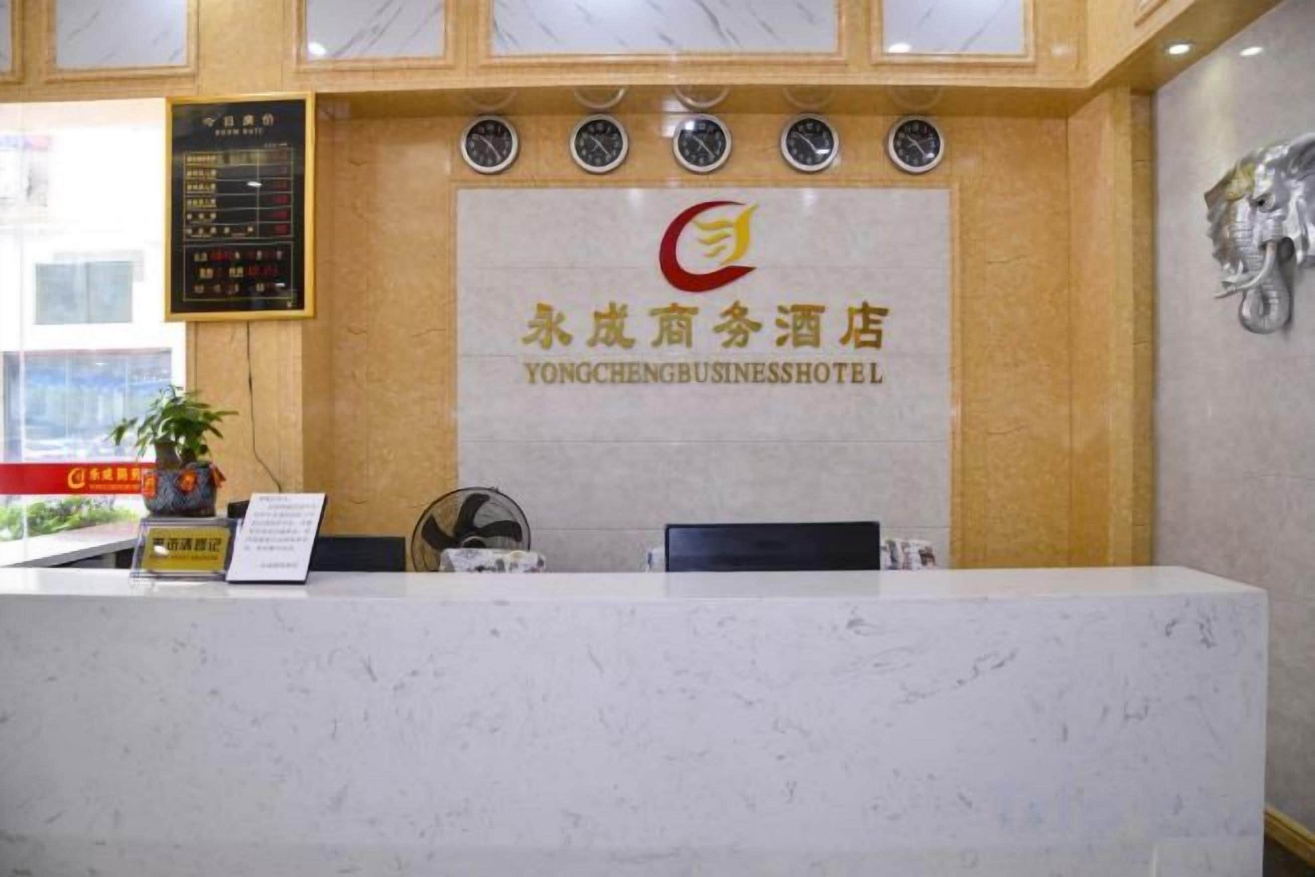 Una recepción con encimera de mármol, un reloj y un cartel del Hotel Yongcheng Business.