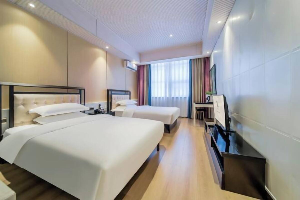 Ein Hotelzimmer mit zwei Betten, einem Schreibtisch und einem Fernseher.