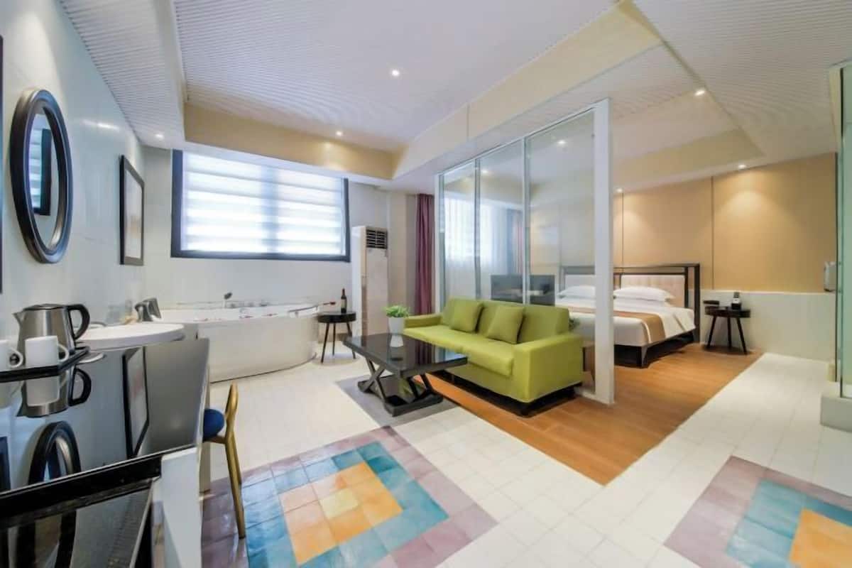 Ein modernes Hotelzimmer mit einer Couch, einem Bett, einem Schreibtisch und einem Badezimmer.