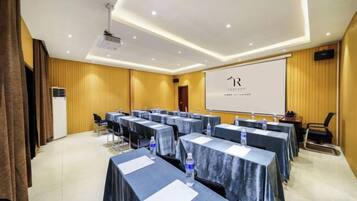 A conference room with tables, chairs, a projector, and a presentation screen.