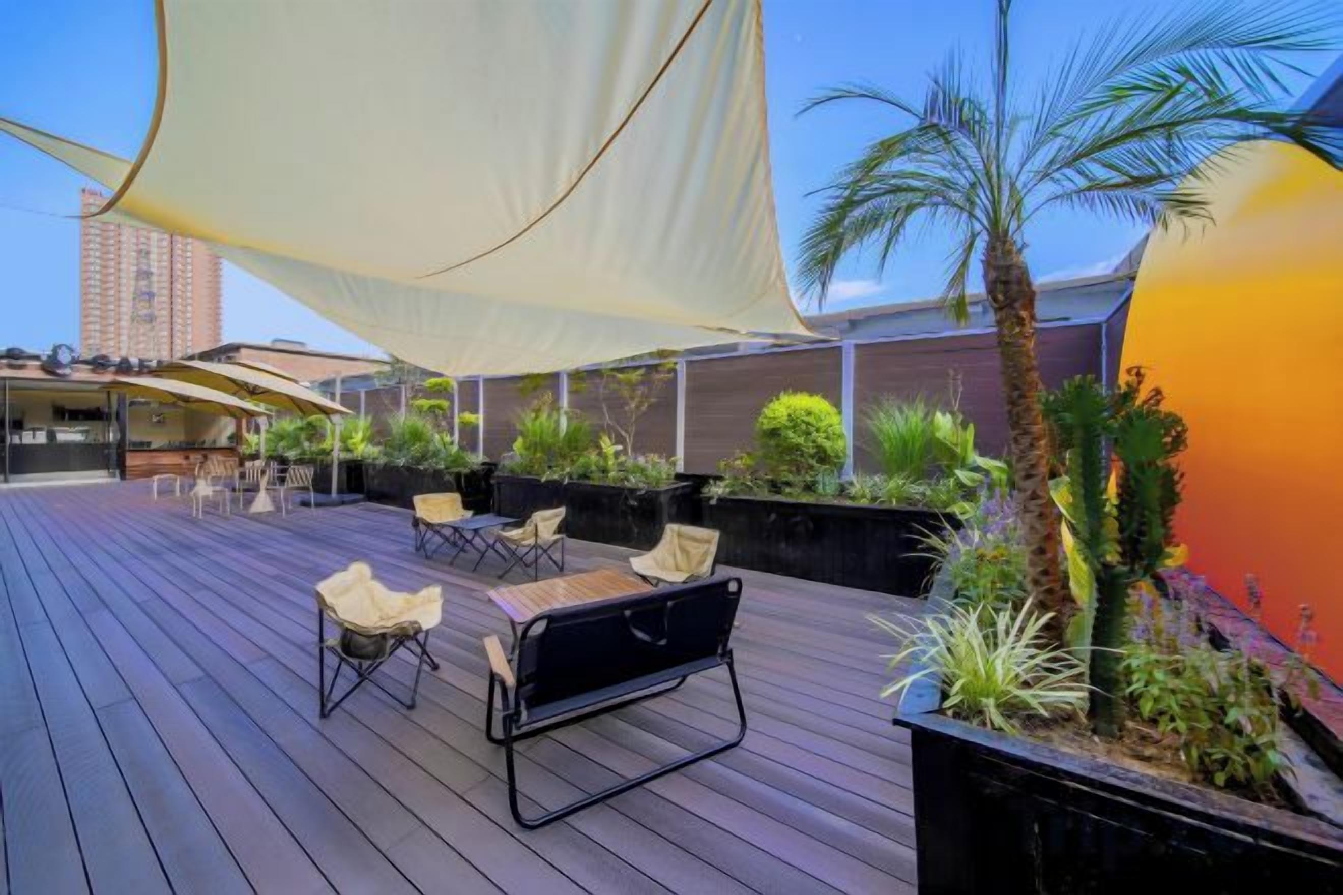 Terraza exterior con asientos, plantas y una vela de gran tamaño.