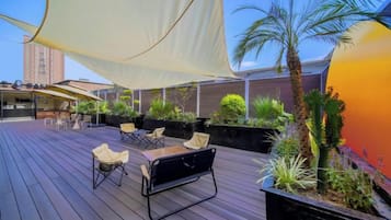 Terraza exterior con asientos, plantas y una vela de gran tamaño.