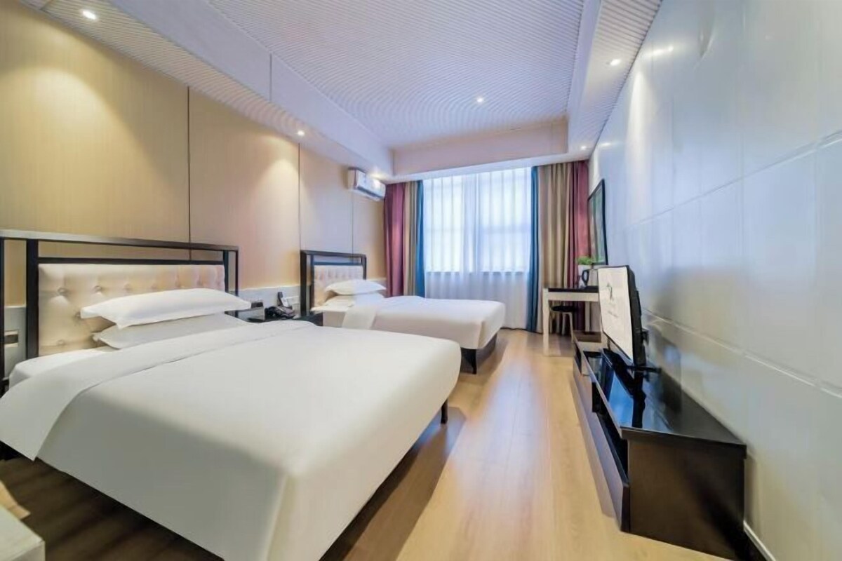 Ein Hotelzimmer mit zwei Betten, einem Schreibtisch und einem Fernseher.