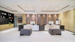 Un espace d’accueil moderne comprenant un comptoir de réception, deux canapés gris et un climatiseur fixé au mur.
