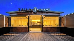 Un bâtiment moderne, avec une enseigne indiquant « TAILS OF THE SEA » à l’entrée.