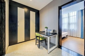 Ein modernes Zimmer mit Schreibtisch, Stuhl und Bett. Eine Tür mit schwarzem Rahmen und ein Fenster mit Vorhängen sind vorhanden.