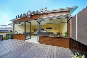 Una cafeteria moderna amb terrassa de fusta, entrada de vidre i cuina oberta.