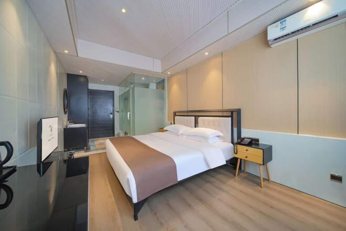 Ein modernes Hotelzimmer mit einem großen Bett, Nachttischen und einer Klimaanlage.