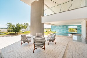 A modern outdoor patio with a pool, lounge chairs, and a view of the landscape.