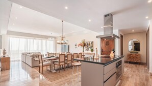 A spacious living room with a large sofa, dining area, and kitchen with a central island. - Brand new Aparment w 3BR in Cap Cana (Punta Cana)