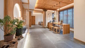 Un interior moderno con techo de madera, una mesa de recepción y una zona de estar con vistas amplias a través de grandes ventanales.