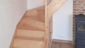 Un escalier en bois, un mur en briques et un meuble de couleur sombre.