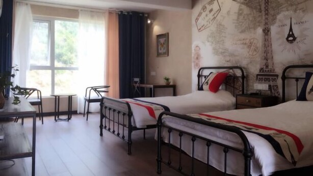 A hotel room with two beds, a desk, chairs, a window with curtains, and a wall with travel-themed decorations. - AA Hotel Chain Lianyungang Jinxu Garden Branch (Lianyungang)
