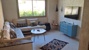 Una sala de estar con sofá, mesa de centro, televisor y una alfombra estampada.