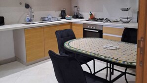 Una cocina compacta con armarios de madera, estufa a gas, lavabo y una mesa de comedor con sillas.