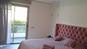 Un dormitorio con una cama grande, una puerta corrediza de vidrio a un balcón y una lámpara en el techo.