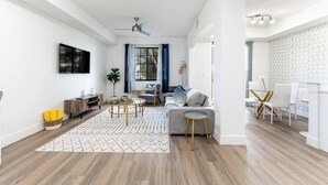 A modern living room with a grey sofa, a coffee table, and a TV mounted on the wall.