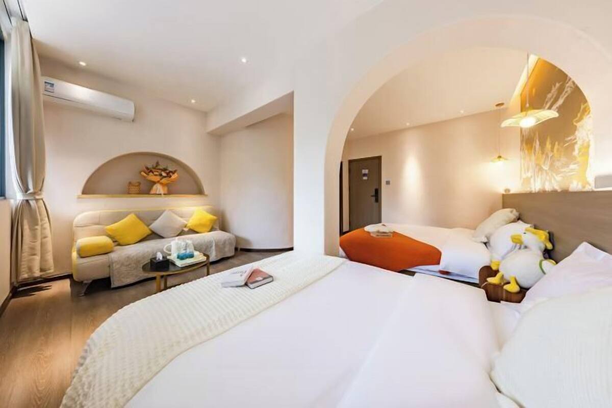 A hotel room with a bed, a sofa, a small table, and a decorative wall.