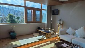 A modern living room with a sofa, a coffee table, and a view of the outdoors through large windows. - Yunqi Chinese Inn (Kunming Dianchi Haigeng Dam) (Kunming)
