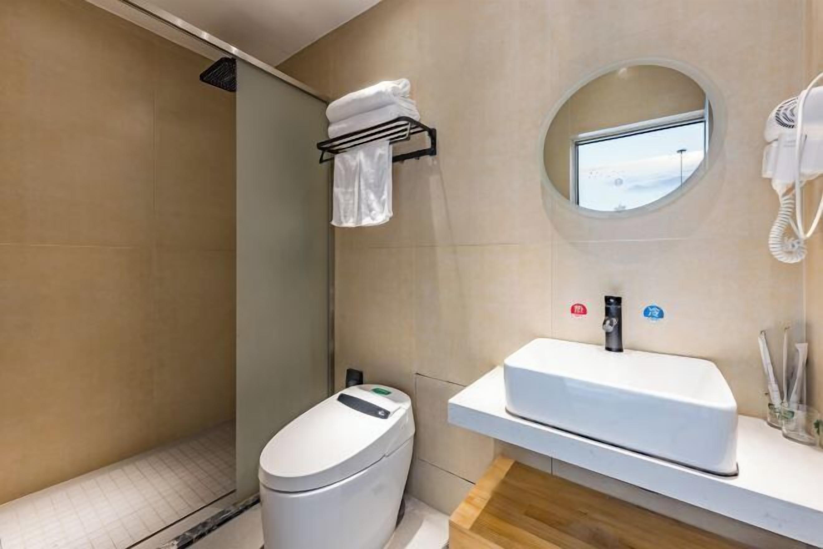 A modern bathroom with a toilet, a sink, a towel rack, a hairdryer, and a small window.