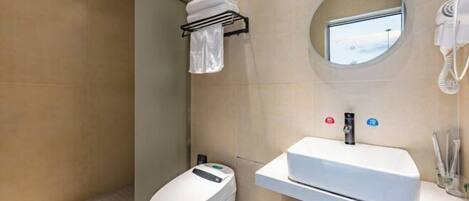 A modern bathroom with a toilet, a sink, a towel rack, a hairdryer, and a small window.