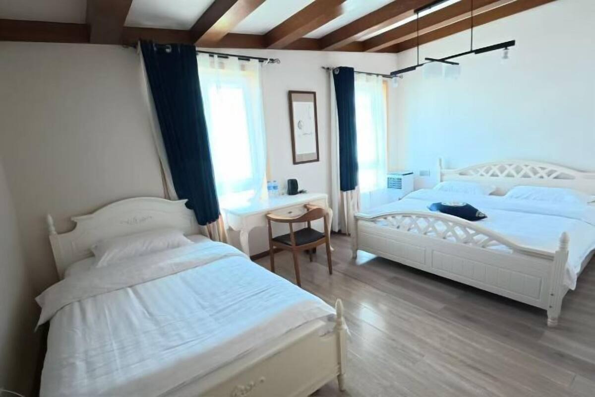 A bedroom with two beds, a desk, and a chair.