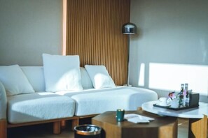 A modern hotel room with a white sofa, a wooden accent wall, a floor lamp, and a small table with a tray of toiletries. - Yunqi Chinese Inn (Kunming Dianchi Haigeng Dam) (Kunming)