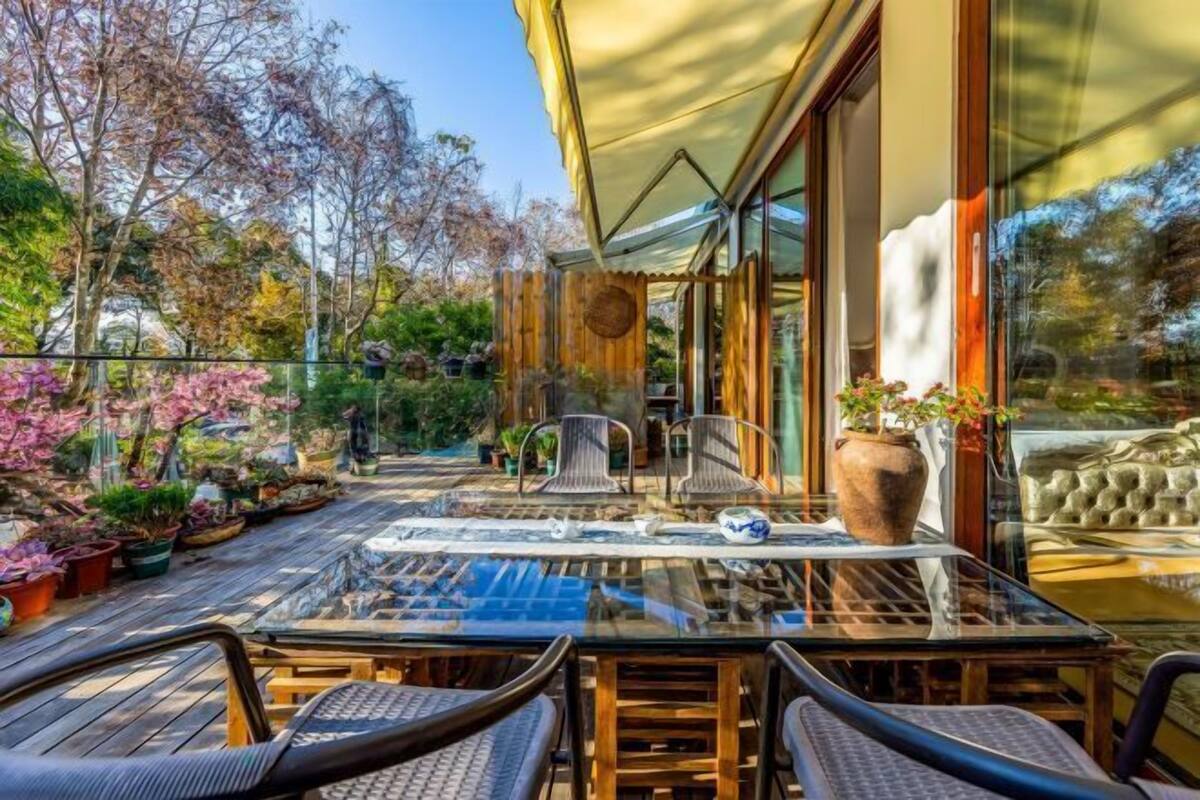 An outdoor patio with a glass table, chairs, and potted plants.