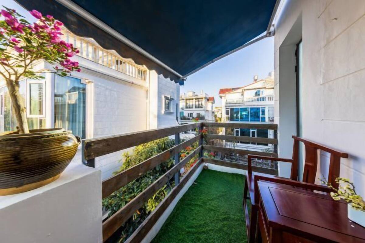 A balcony with a wooden railing, a potted plant, and a small table.