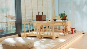 A cozy seating area with a cushioned bench, a wooden table with a tray, and a potted plant. - Yunqi Chinese Inn (Kunming Dianchi Haigeng Dam) (Kunming)