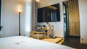 A modern hotel room with a large bed, a desk with a chair, a flat-screen TV mounted on the wall, and a wooden wardrobe. - Yunqi Chinese Inn (Kunming Dianchi Haigeng Dam) (Kunming)