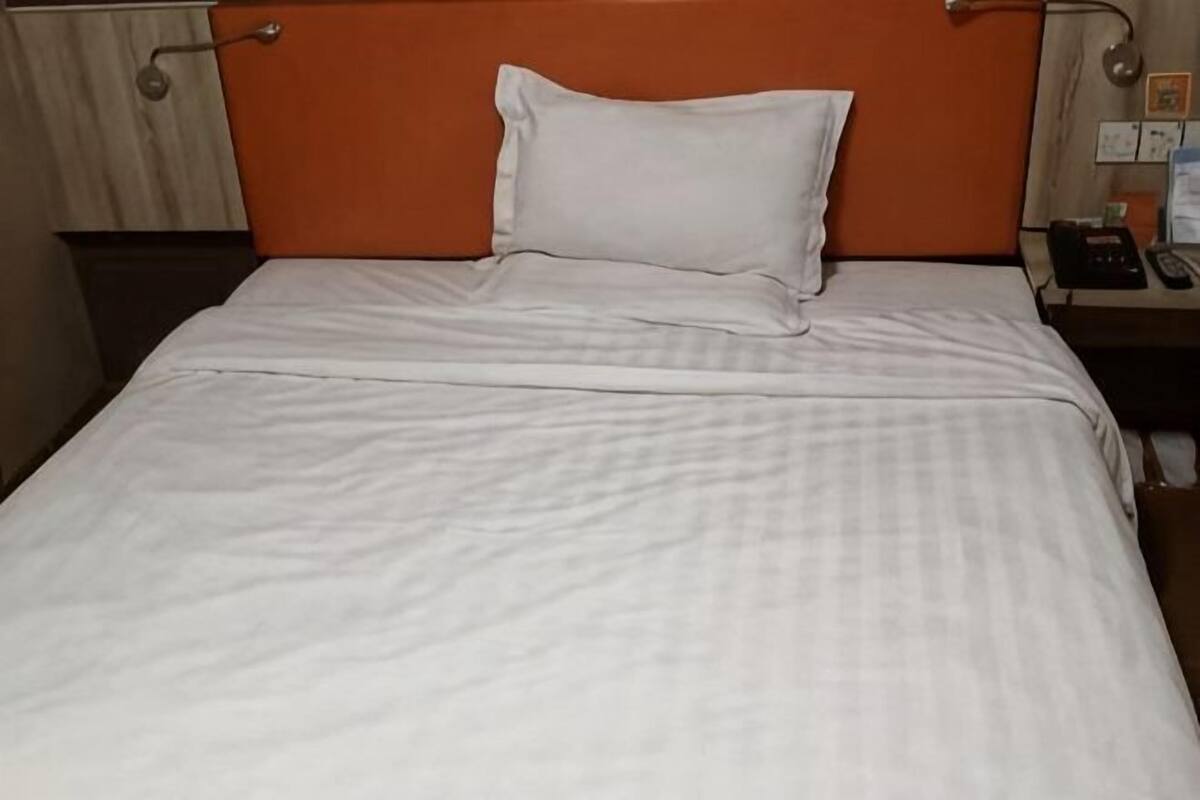 Ein Bett mit weißer Bettdecke und einem einzelnen weißen Kopfkissen.