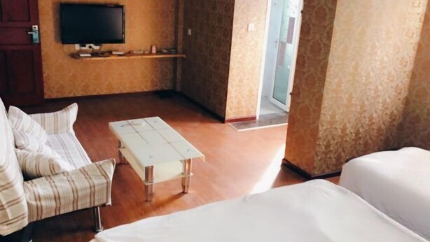 A hotel room with a sofa, a small table, a television, and a door leading to another room.