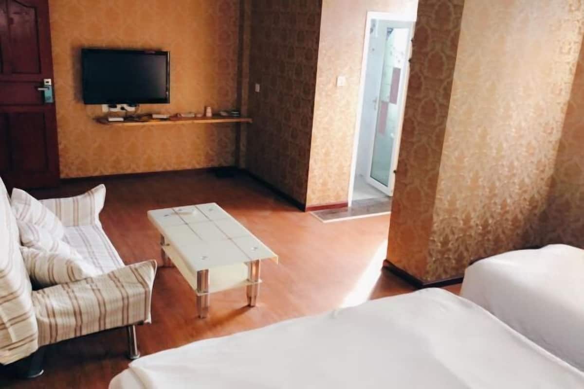Ein Hotelzimmer mit einer Couch, einem kleinen Tisch, einem Fernseher und einer Tür zu einem anderen Raum.