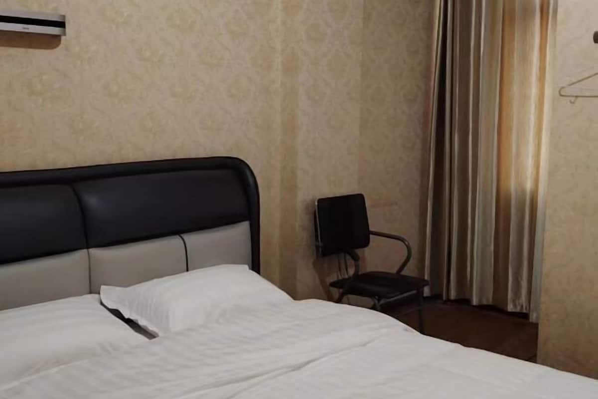 Ein Hotelzimmer mit Bett, Sessel, Lautsprecher und Vorhang.