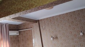 A room with patterned wallpaper, a white ceiling, and a light fixture.
