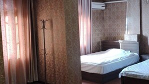 A bedroom with two beds, a wardrobe, and an air conditioning unit.