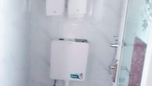 A bathroom with a white tiled wall, a white toilet, and a glass shower enclosure.