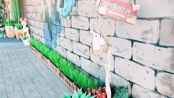 A stone wall with a sign, potted plants, and a small deer statue.
