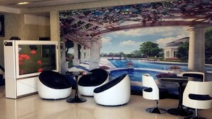 A room with a mural of a garden, a fish tank, and modern seating. - Riverside Hotel (Dalian)