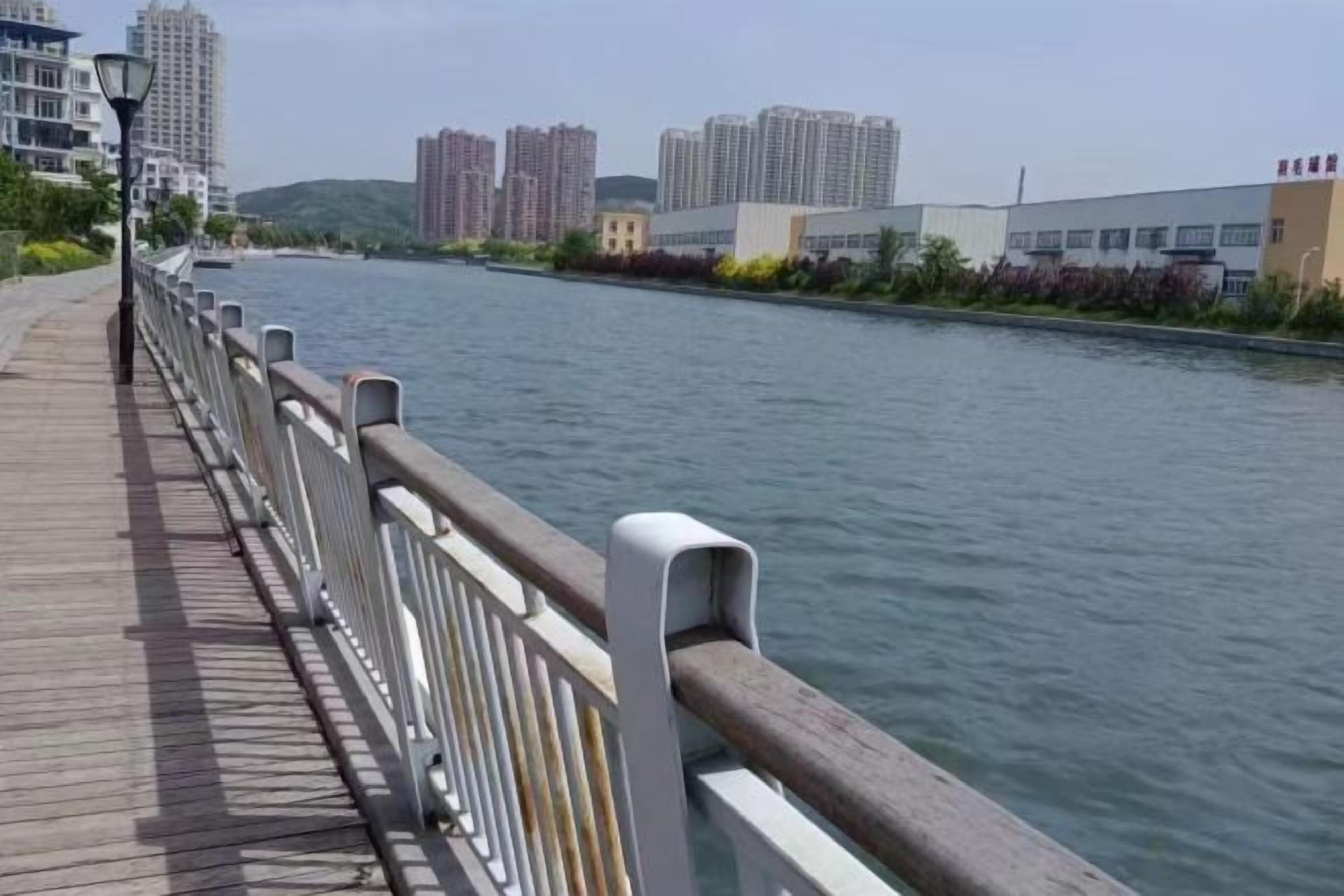 A riverside walkway with a wooden deck and metal railing.