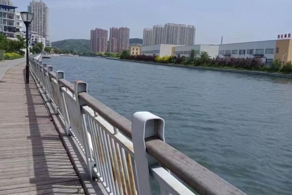 A riverside walkway with a wooden deck and metal railing. - Riverside Hotel (Dalian)