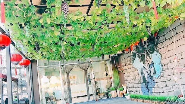 A hotel entrance with a glass facade, a mural on the wall, and a hanging vine decoration. - Riverside Hotel (Dalian)
